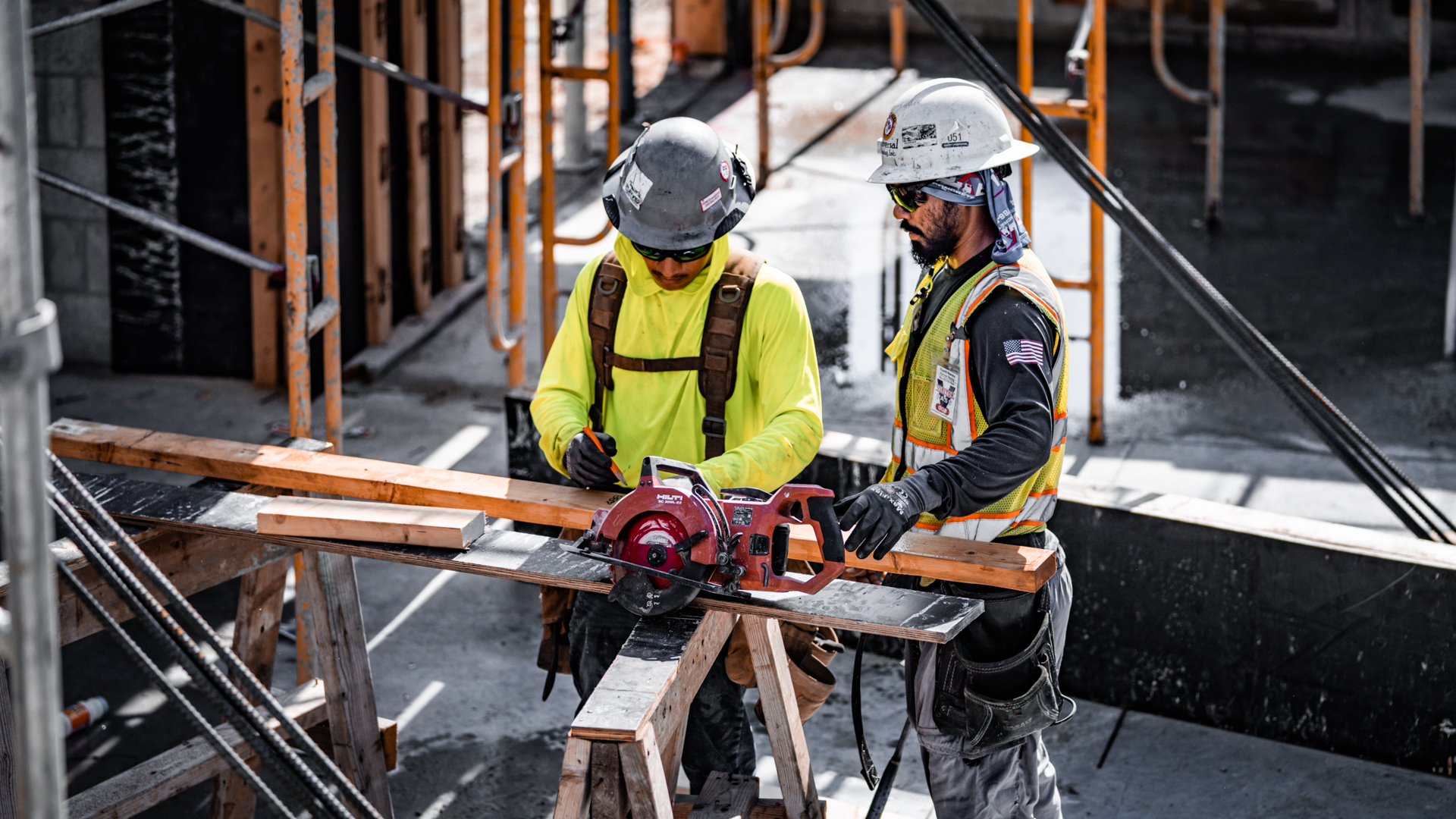 Impact Concrete carpenters measuring and cutting lumber for formwork